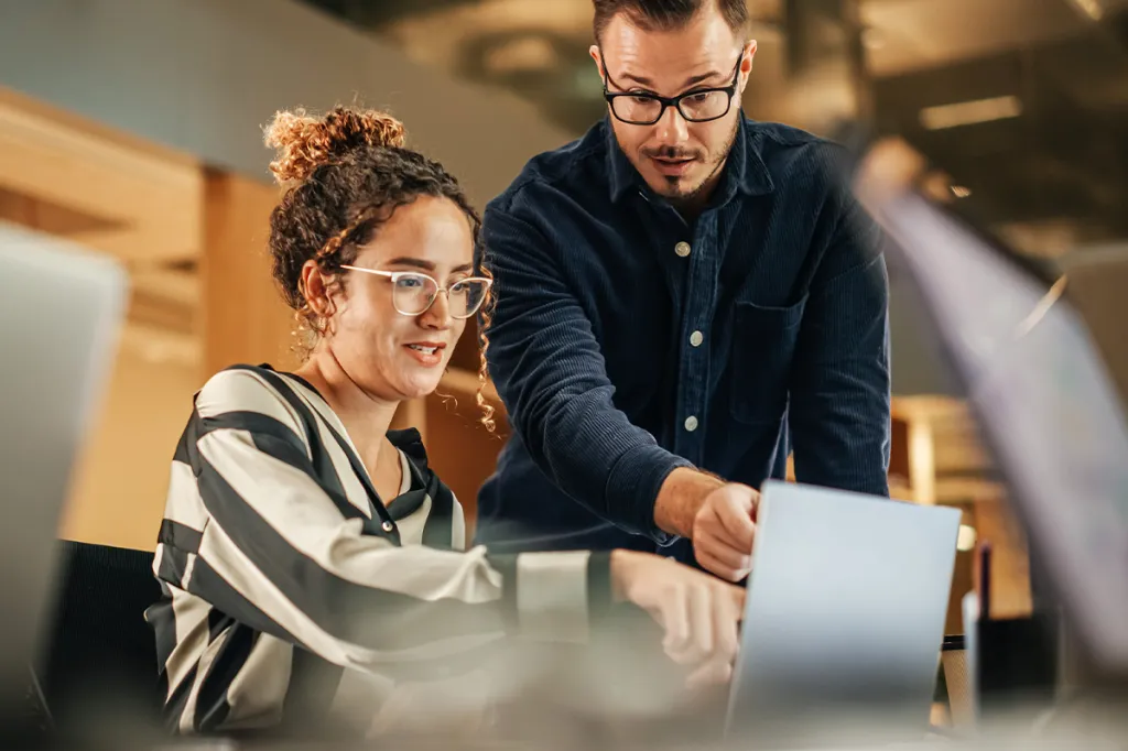 Man and woman using ChatGPT or generative AI on a laptop